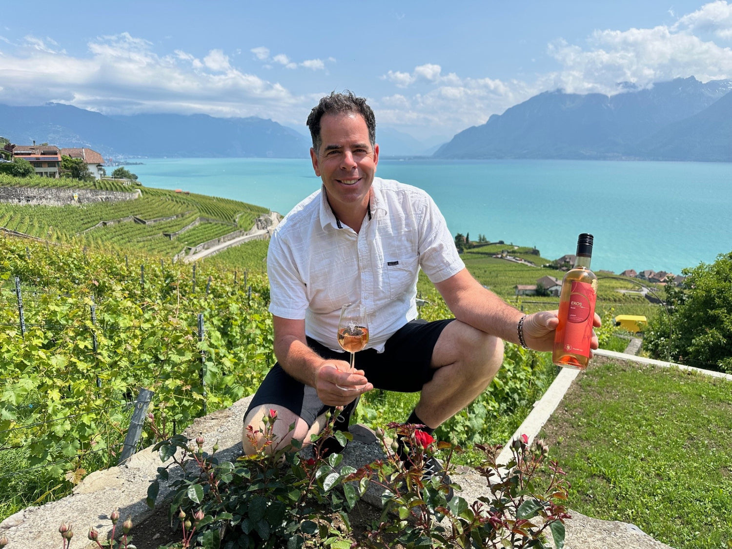 Christophe Francey souriant avec un verre de rosé Francey Vins, assis dans un cadre convivial à Lavaux.
